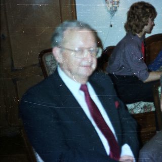 Men in suits and a woman seated in a room.