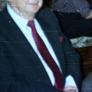 Men in suits and a woman seated in a room.