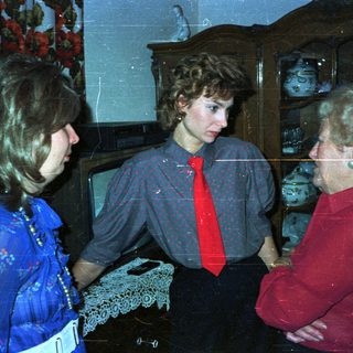 Three people standing indoors, likely engaged in conversation.