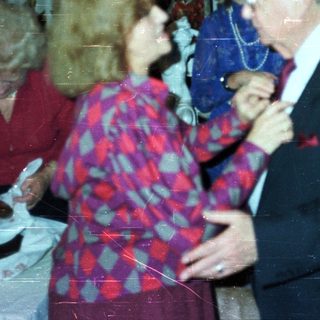 Couple dancing at a party with onlookers.