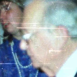 Couple dancing at a party with onlookers.