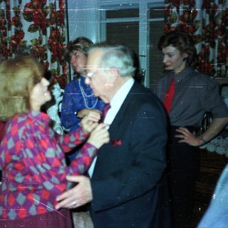 Couple dancing at a party with onlookers.