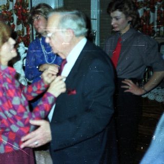 Couple dancing at a party with onlookers.