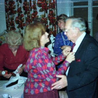 Couple dancing at a party with onlookers.
