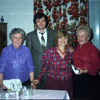 Four people stand near a table with a cake.