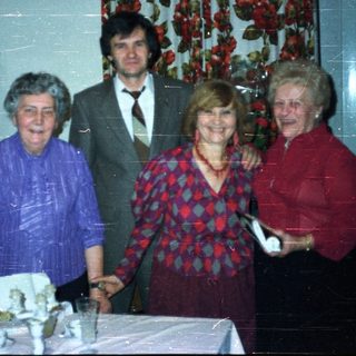 Four people stand near a table with a cake.