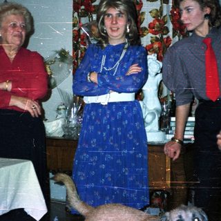 A family gathering indoors with patterned wallpaper and decor.