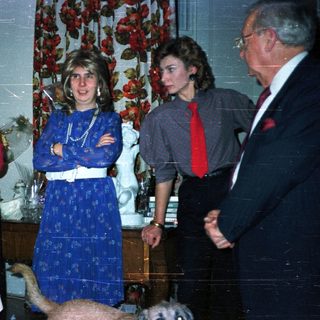 A family gathering indoors with patterned wallpaper and decor.