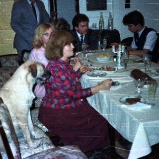 Family dining at a table with a dog present.