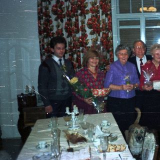 Group of people celebrating, with a dog and table setting.