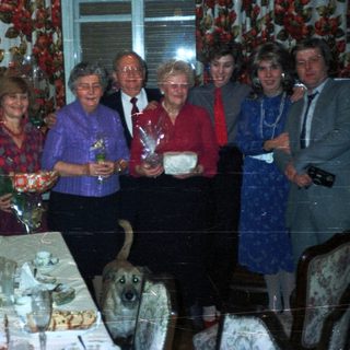 Group of people celebrating, with a dog and table setting.