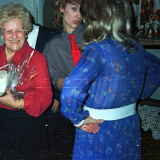Woman receives gift, smiling, in a warmly decorated room.
