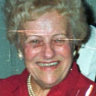 Woman receives gift, smiling, in a warmly decorated room.