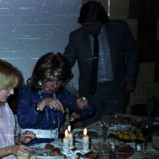People dine at a formal table with candles and a server.