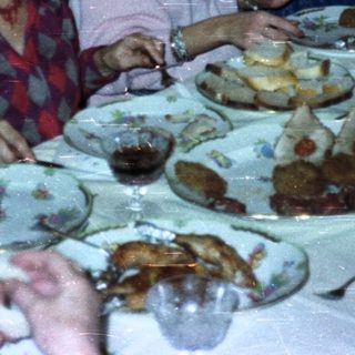 People dine at a formal table with candles and a server.