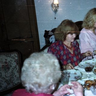 People dine at a formal table with candles and a server.