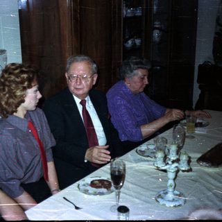 Here's a brief summary of the image: Three people seated at a table with glassware.
