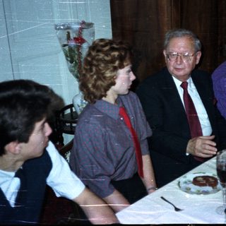 Here's a brief summary of the image: Three people seated at a table with glassware.