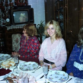 Women at a formal dinner table in a vintage setting.