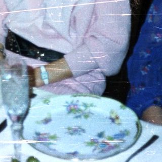 Women at a formal dinner table in a vintage setting.