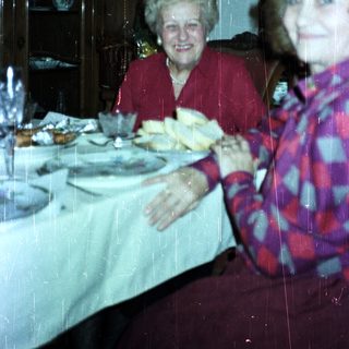 Two women seated at a table with a decorated sideboard.