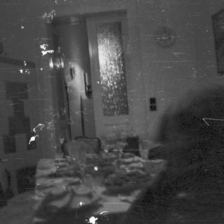 Dark room with a table, chairs, and a doorway.