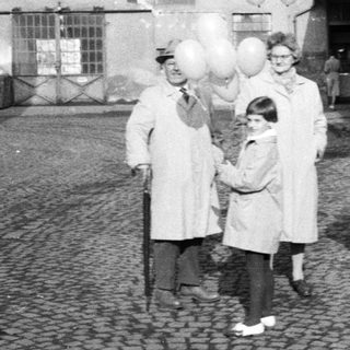 Group with balloons standing outside a building.