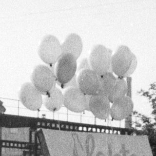 Men parade a May Day banner with balloons.