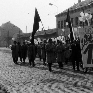 Parade with flags and banners on a cobblestone street.