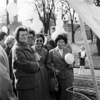Group of people standing near balloons in an outdoor setting.