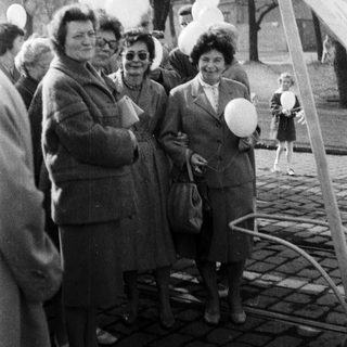Group of people standing near balloons in an outdoor setting.