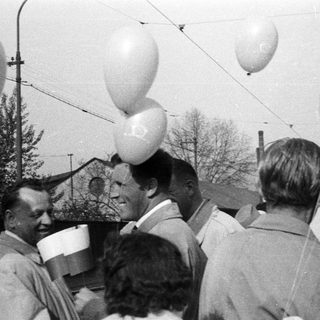 Group of men gathered, balloons visible in a vintage scene.