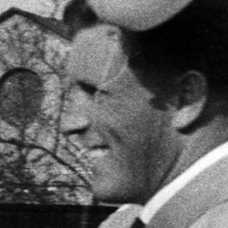 Group of men gathered, balloons visible in a vintage scene.
