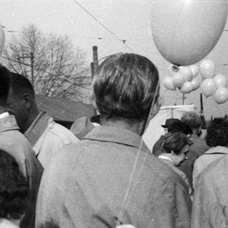 Group of men gathered, balloons visible in a vintage scene.