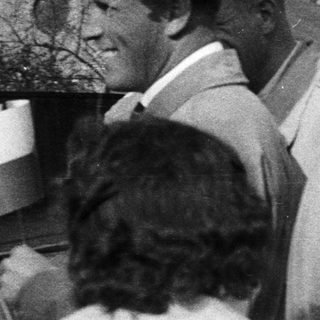 Group of men gathered, balloons visible in a vintage scene.
