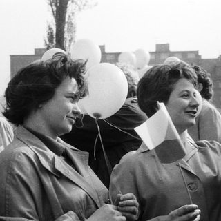 Group of women holding balloons and flags outdoors.