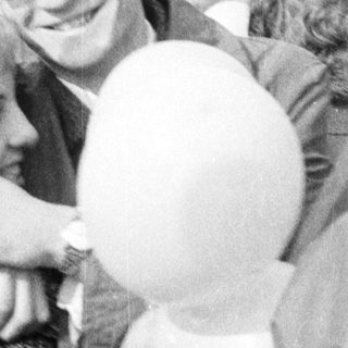 Man embraces a woman outdoors, holding a balloon.
