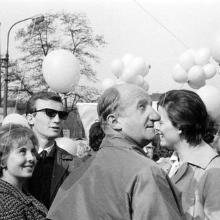 Group of people gathered, some with balloons, in a crowd.