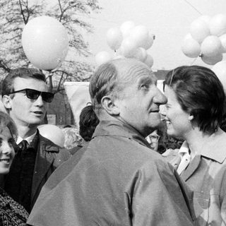 Group of people gathered, some with balloons, in a crowd.