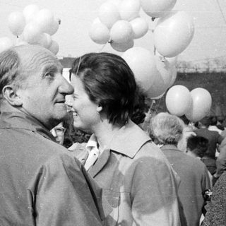 Group of people gathered, some with balloons, in a crowd.