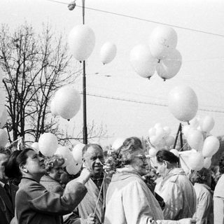 Group gathers, holding balloons; likely a celebration or event.