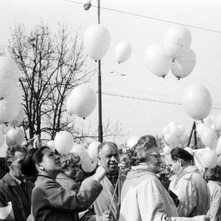 Group gathers, holding balloons; likely a celebration or event.