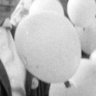 Group of people stand with balloons in a black and white photo.