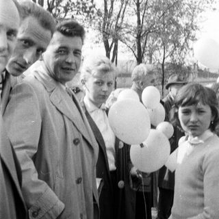 Group of people stand with balloons in a black and white photo.