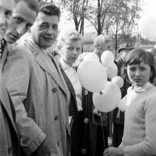 Group of people stand with balloons in a black and white photo.