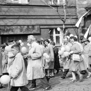 Black and white photo depicts a group marching with balloons.