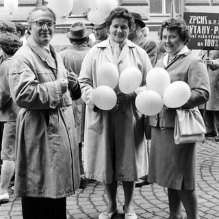 Three people hold balloons in a black and white photo.