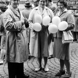 Three people hold balloons in a black and white photo.
