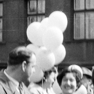 Group of people holding balloons, black and white photograph.