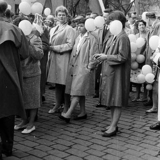 Group of people holding balloons in a public space.